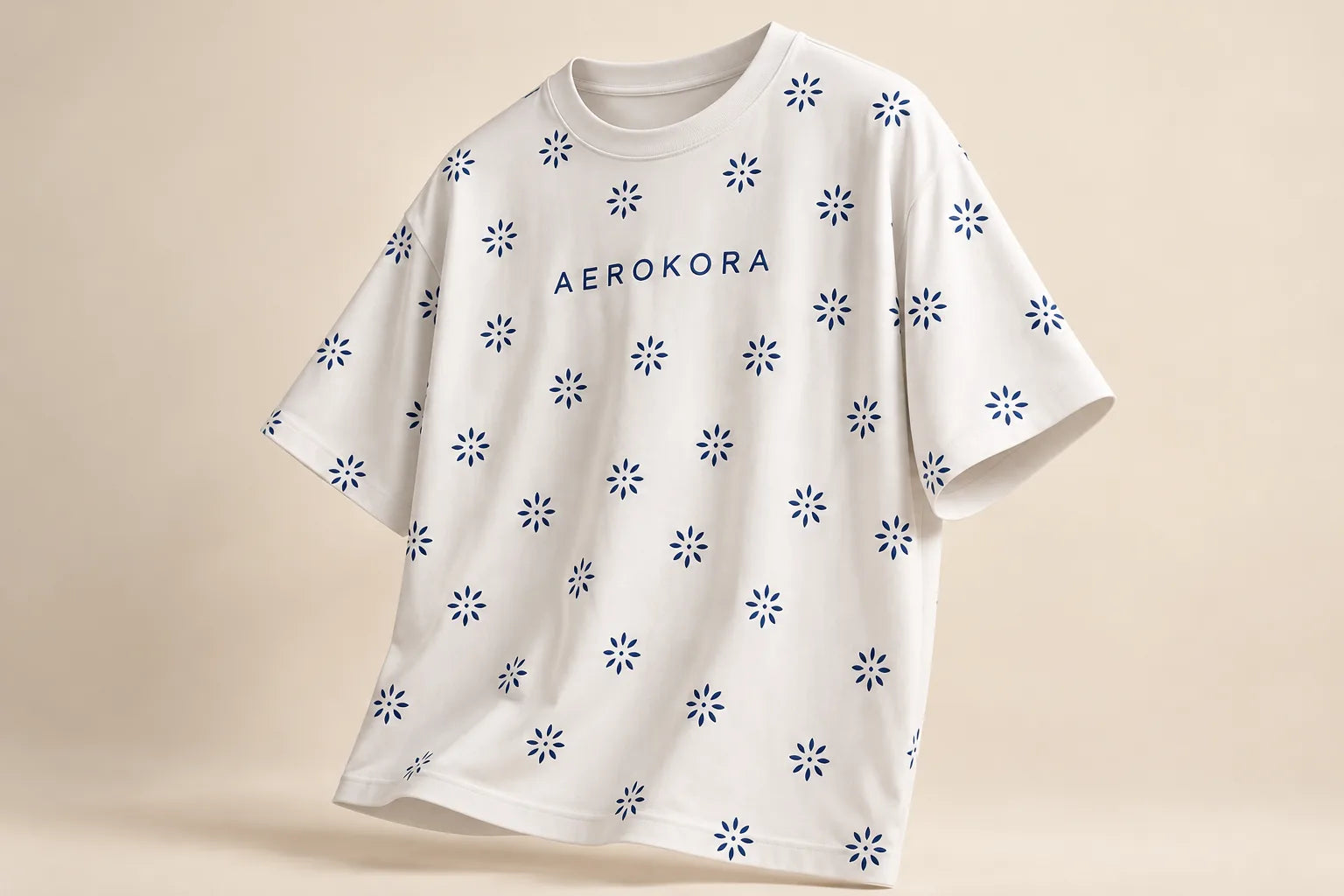 White AEROKORA tee with a navy daisy print, on a warm studio backdrop