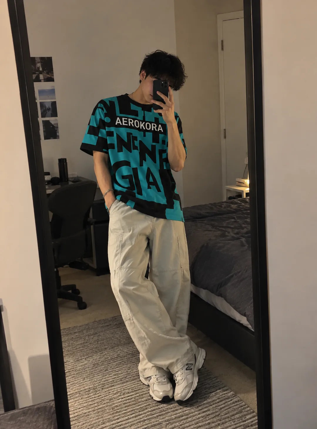 Mirror selfie in a teal and black AEROKORA graphic tee with wide cream trousers
