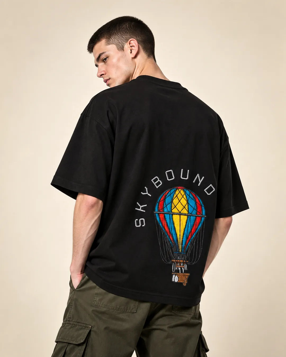 Back of a black Skybound tee with a hot-air balloon print, worn with olive cargos