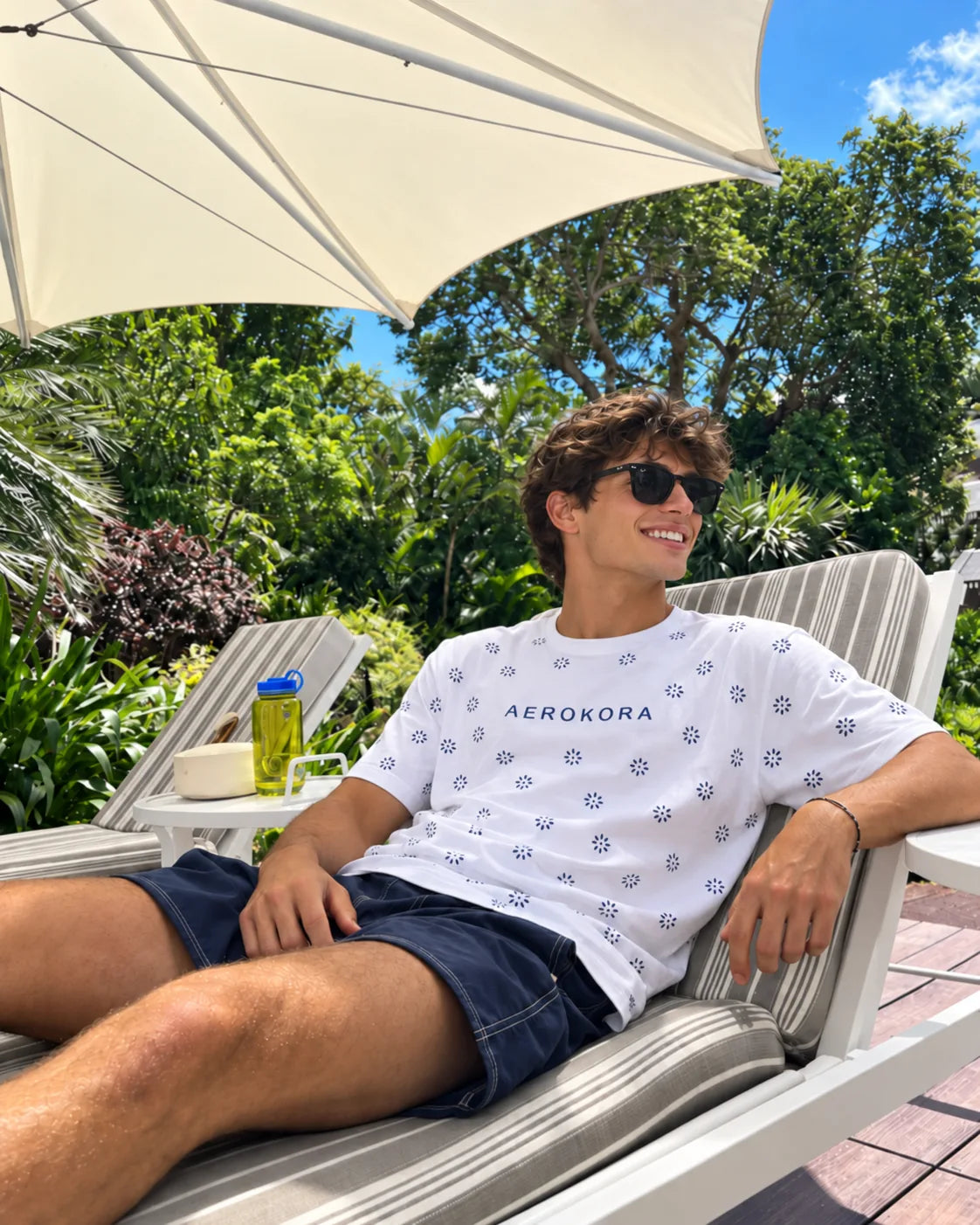 White patterned AEROKORA tee, lounging poolside in the sun